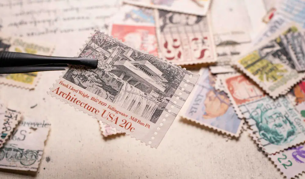 Tweezers holding a postage stamp over a collection