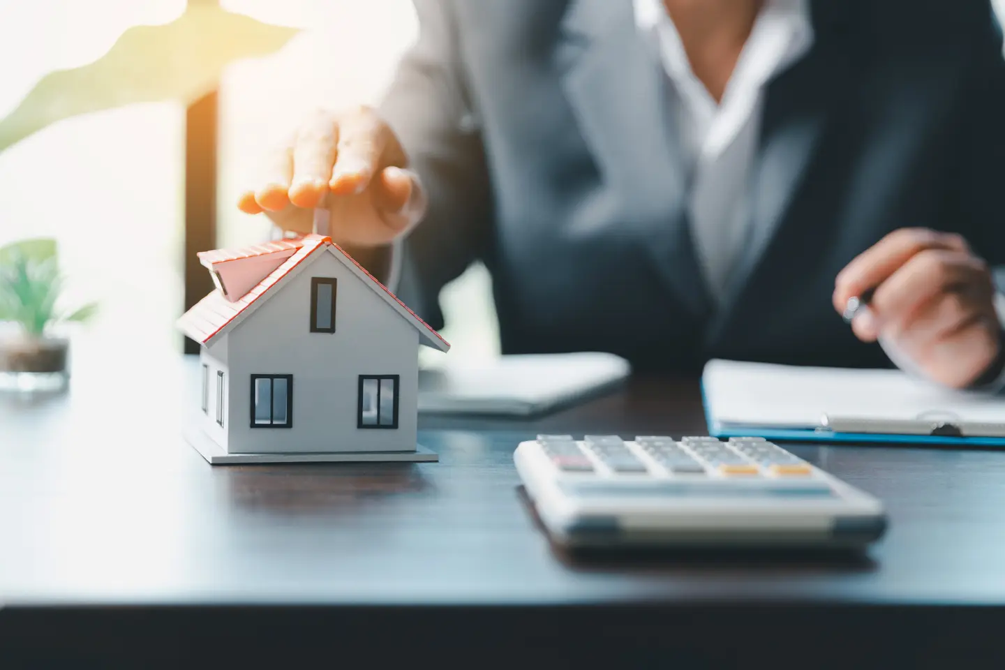 woman in suit hand over model house calculator