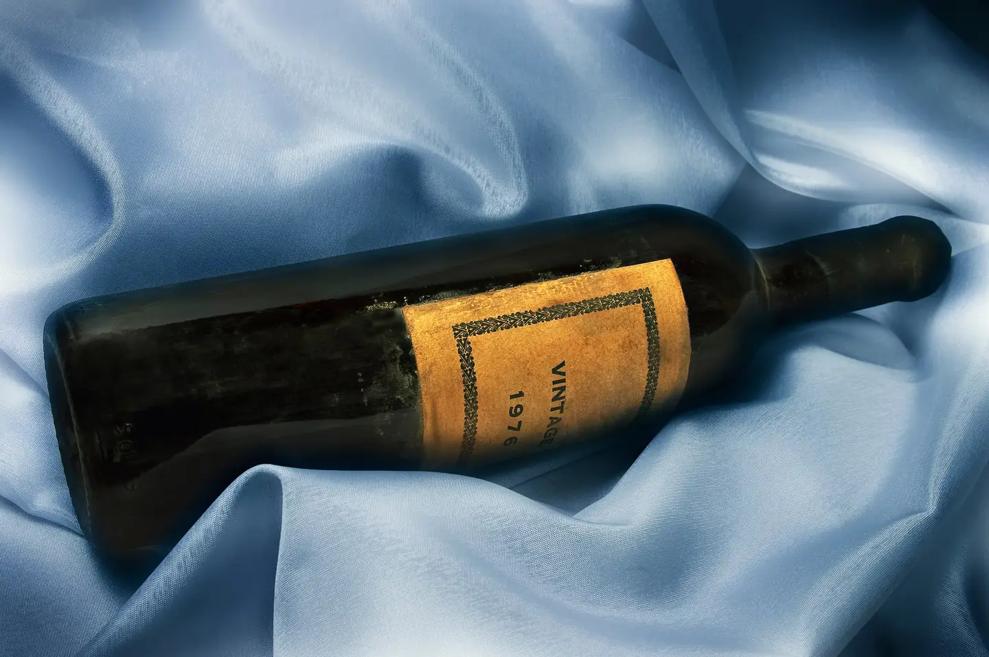 Vintage bottle of wine resting on blue silk