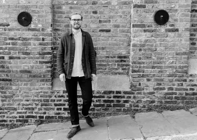 smiling man in front of brick wall black and white