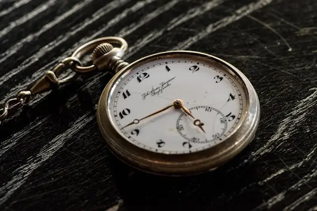 Antique silver pocket watch on a dark wooden surface